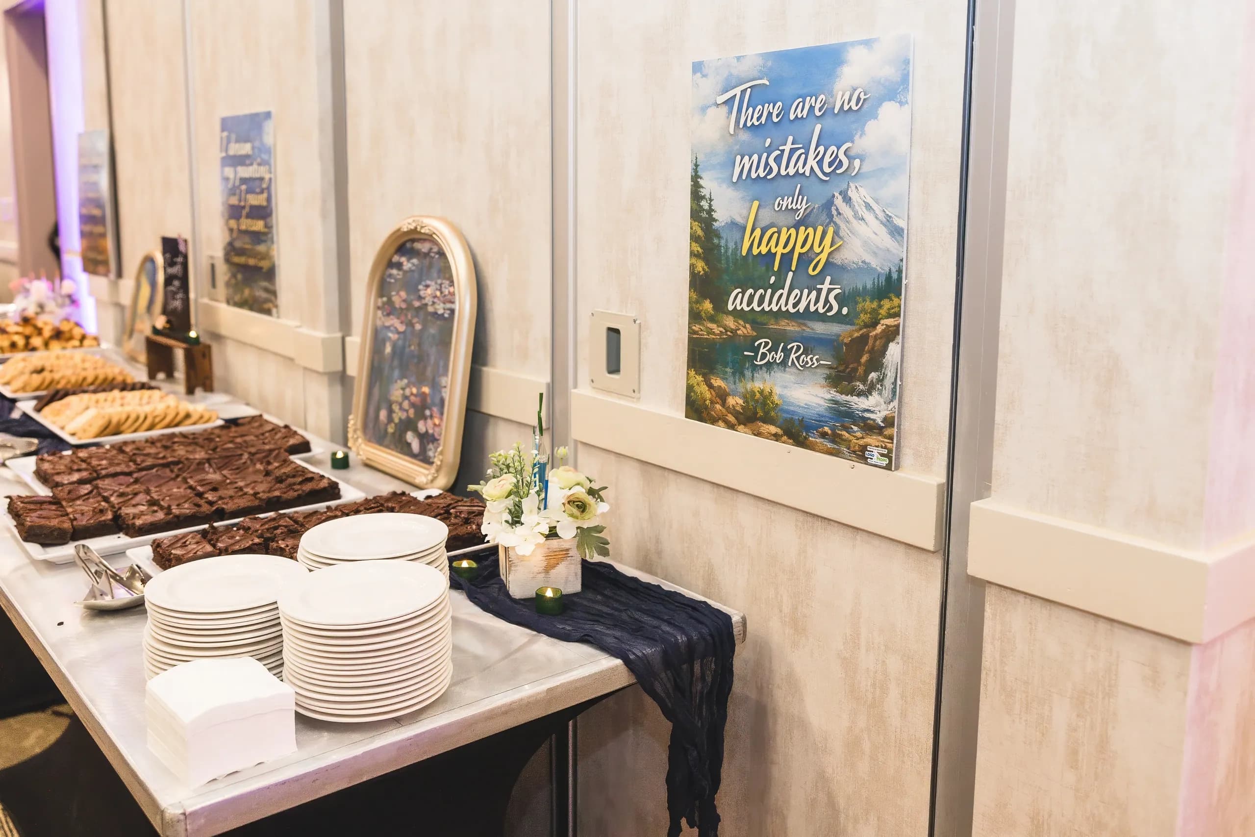 A dessert table beside a poster reading: there are no mistakes, only happy accidents.