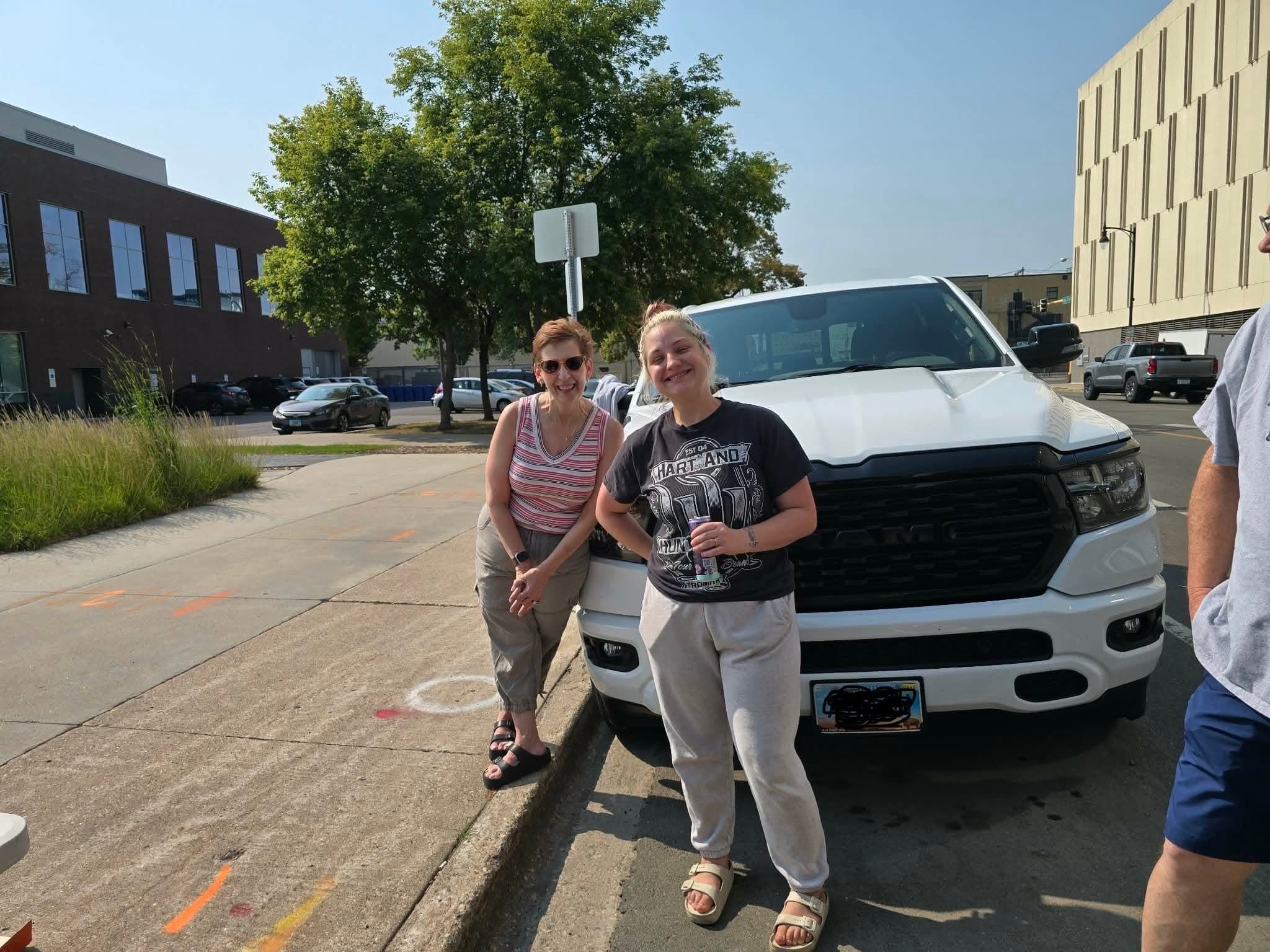 Two Blame Bates team members downtown in Fargo beside a vehicle.
